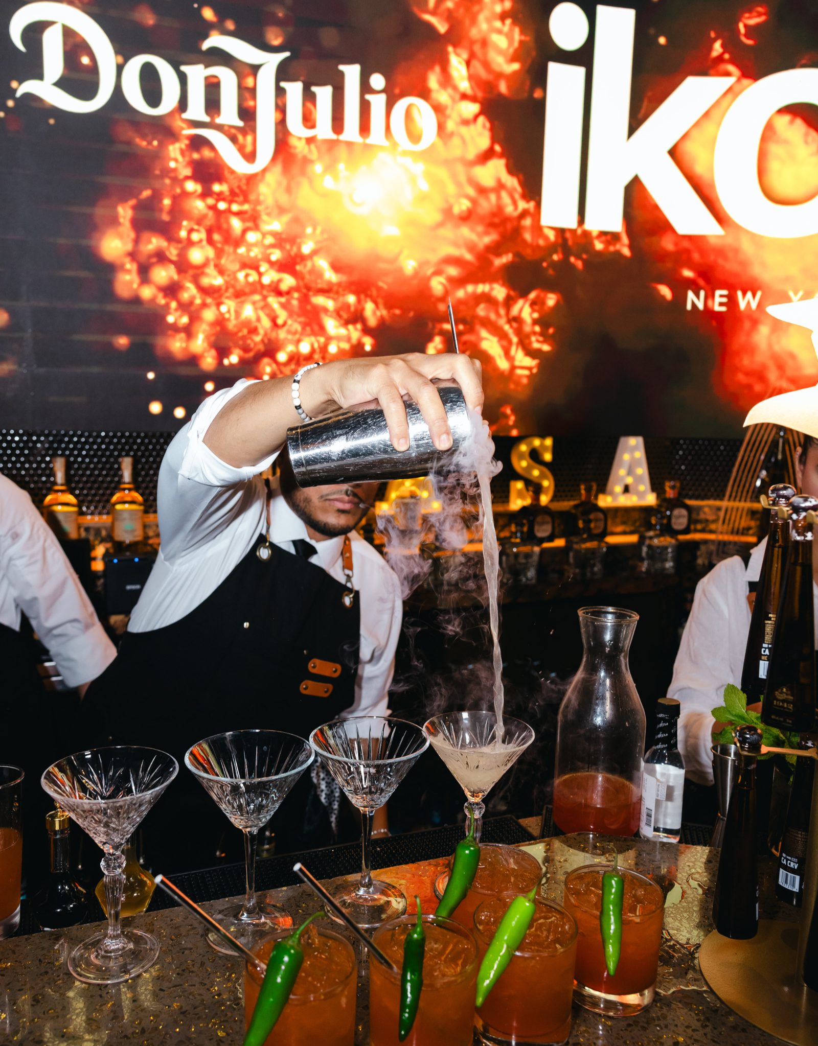 A bartender pouring cocktails in front of the bar display