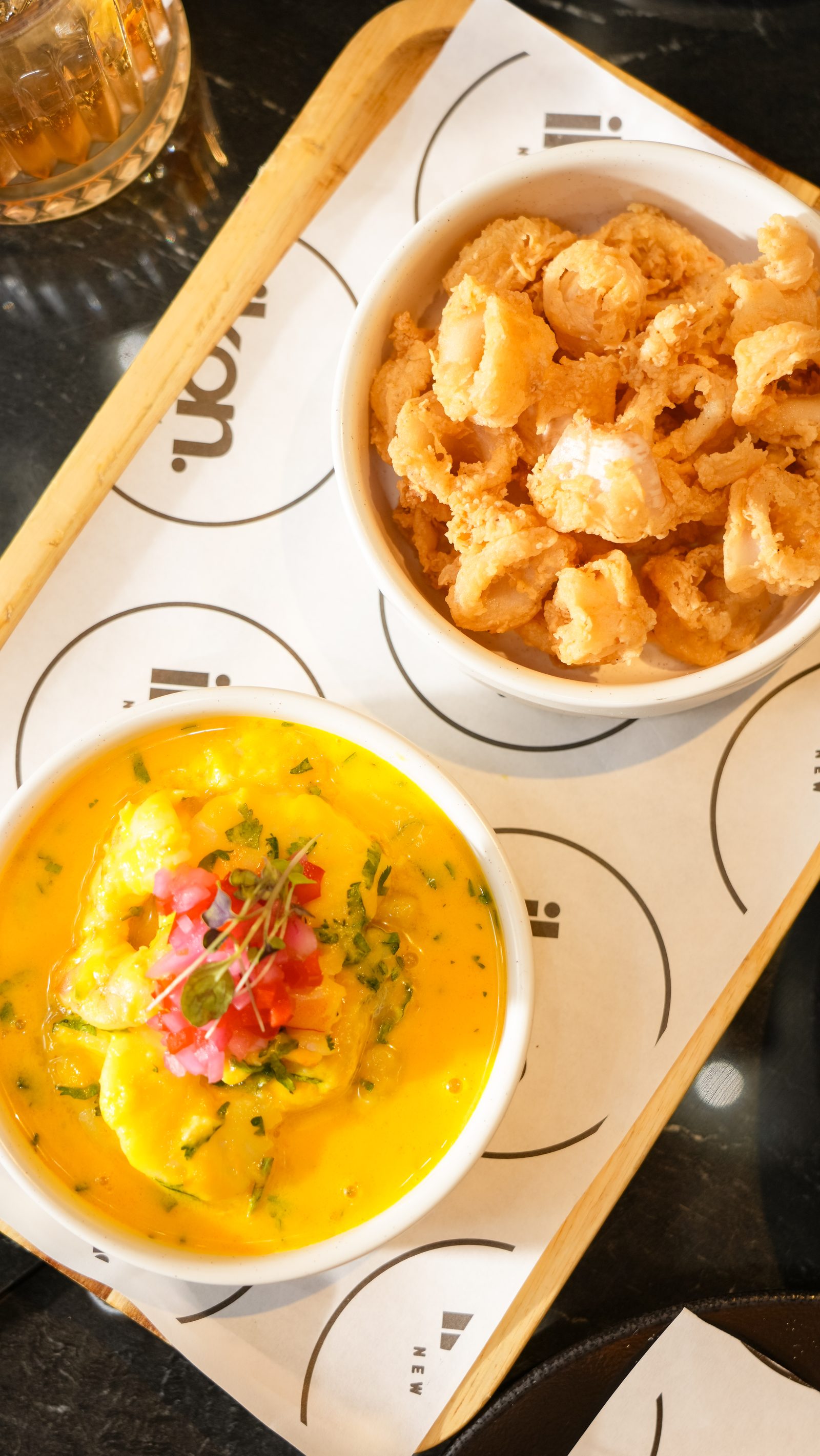 A bowl of ceviche in yellow tiger milk with crisp corn on an IKON tray