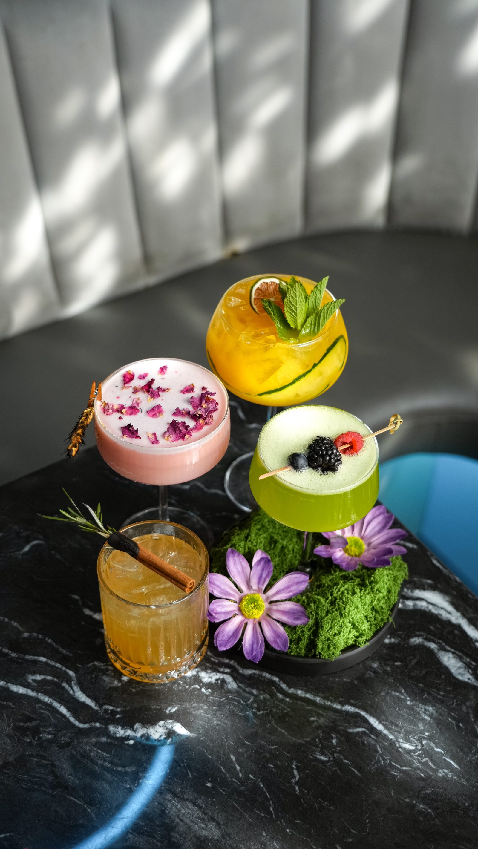 Three signature IKON cocktails garnished with flowers and fruit