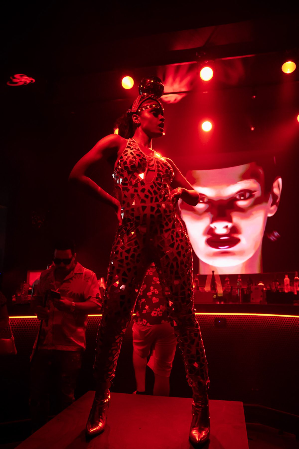 A performer on the runway under red light at IKON