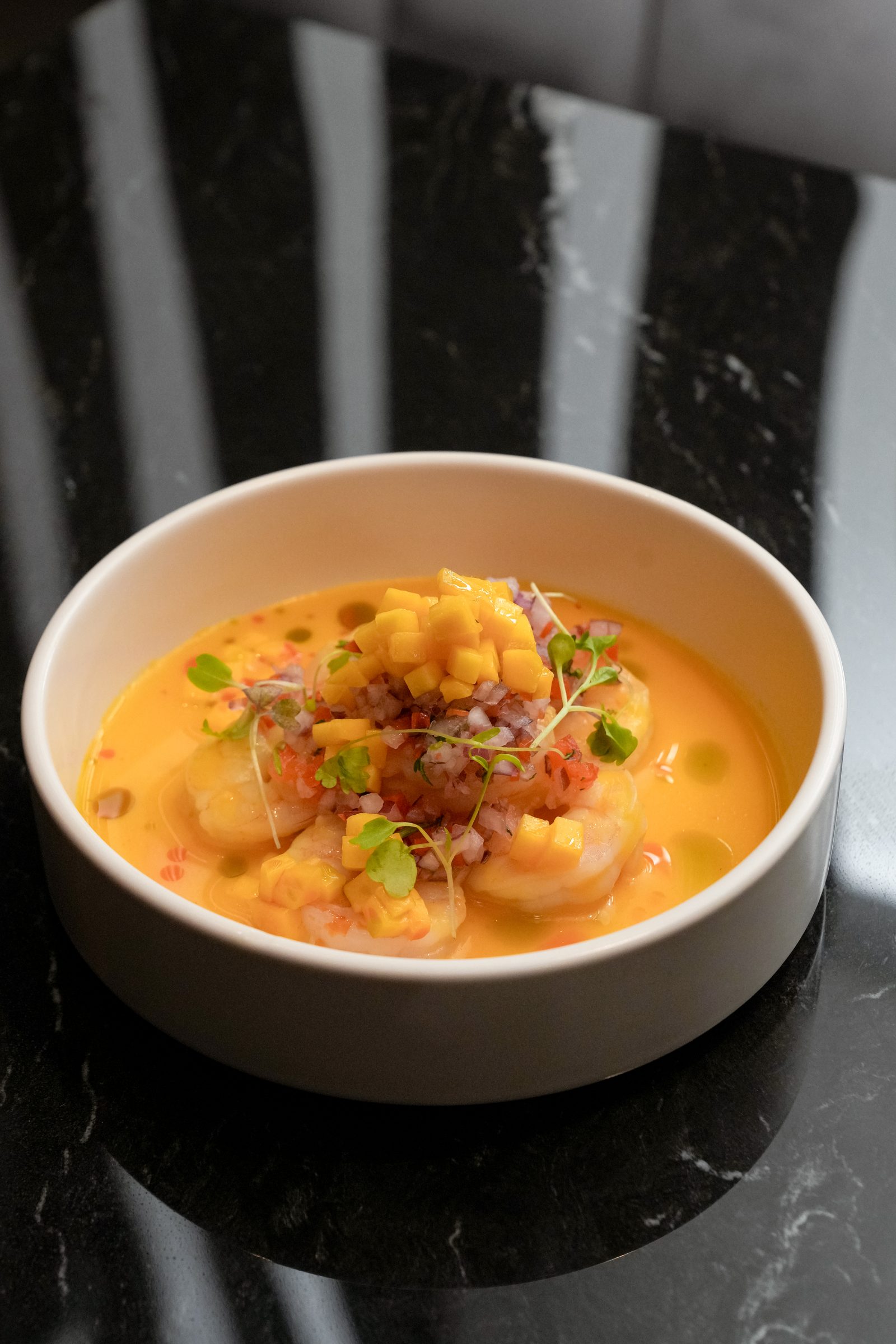 Shrimp in huancaina sauce plated in a white bowl